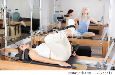 Side view of sports woman stretching body on pilates bed during workout 121738514