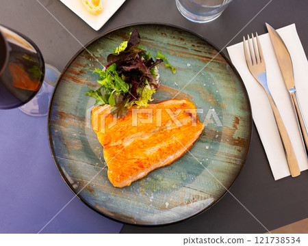 Salmon fillet with salad served on plate 121738534