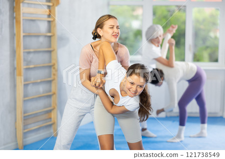Self-defense class - woman learns to fight back an attacking man under the guidance of trainer Self-defense class - woman learns to fight back an attacking man under the guidance of trainer 121738549
