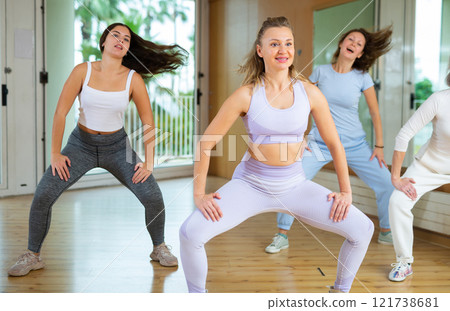 Group of active women of different ages learning new dynamic exercise movements with instructor in dance hall 121738681