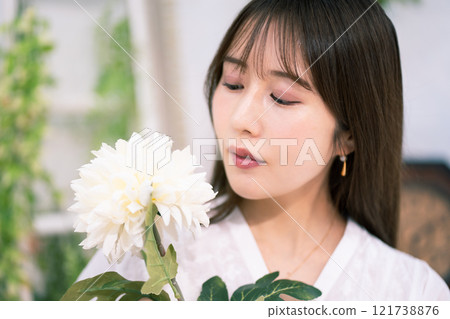 Young woman with long black hair holding white flowers Young woman with long black hair holding white flowers 121738876