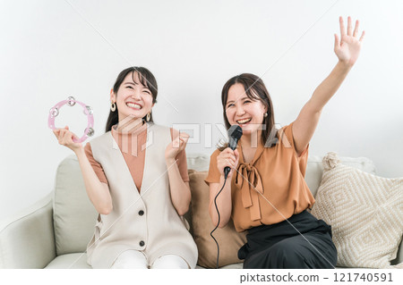 年輕的亞洲女人在家唱卡拉 OK 121740591