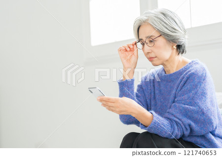 戴著老花眼鏡看智慧型手機的高級女性 121740653