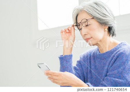 戴著老花眼鏡看智慧型手機的高級女性 121740654