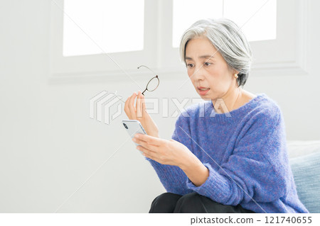 戴著老花眼鏡看智慧型手機的高級女性 121740655