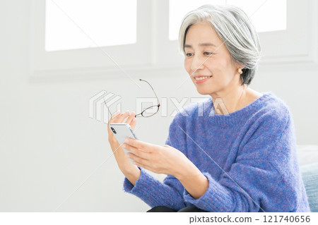 戴著老花眼鏡看智慧型手機的高級女性 121740656