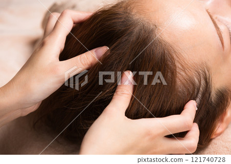 A young Asian woman is getting a head massage. 121740728