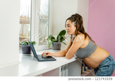 Pregnant woman in casual wear comfortably works from home Pregnant woman in casual wear comfortably works from home 121741039
