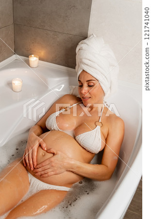 Pregnant Woman Enjoying a Bubble Bath with Candles Description 121741040