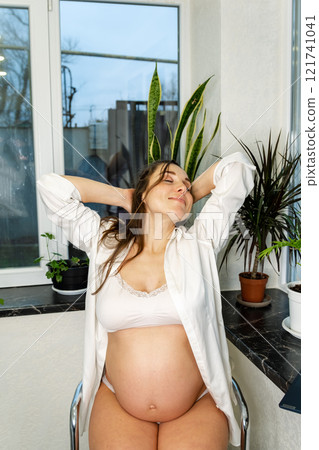 Pregnant Woman Relaxing with Lingerie by the Window Pregnant Woman Relaxing with Lingerie by the Window 121741041