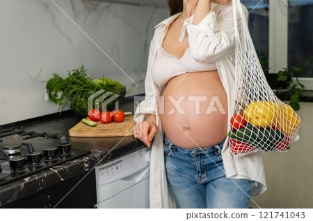 Healthy pregnant woman preapring a fresh salad for her breakfast. 121741043