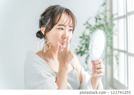 Japanese woman looking in the mirror and checking the pores on her nose 121741203