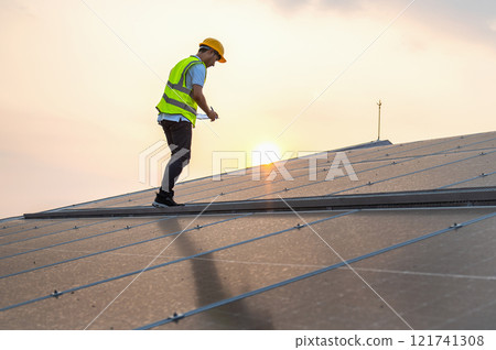 man in a yellow vest is working on a solar panel 121741308
