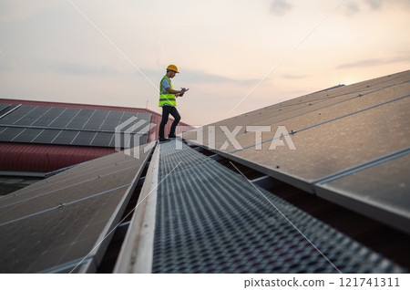 man in a yellow vest is standing on a roof, looking at his phone 121741311