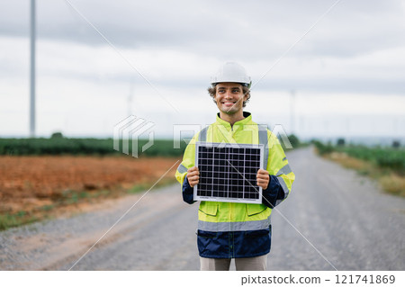 man in a yellow jacket holding a solar panel man in a yellow jacket holding a solar panel 121741869
