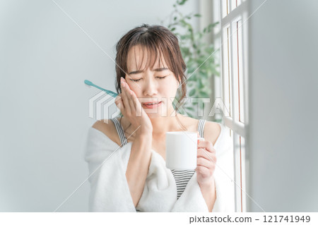 An Asian woman who has a painful tooth decay and holds her cheek 121741949