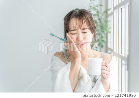 An Asian woman who has a painful tooth decay and holds her cheek 121741950