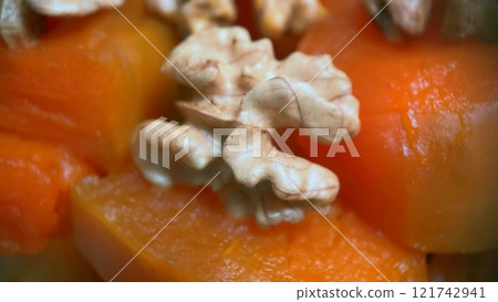 Traditional Turkish Pumpkin Dessert with Walnuts.A delectable close-up of a traditional Turkish pumpkin dessert topped with crunchy walnuts, showcasing its rich texture and vibrant colors.  121742941
