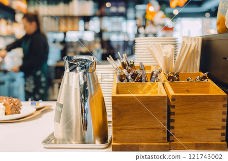 Stainless steel pots and wooden cutlery cases lined up on a cafe counter 121743002