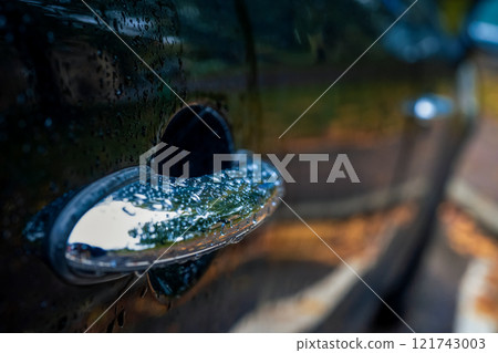 Close-up of a car door handle covered in raindrops 121743003