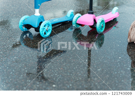A colorful kick scooter reflected in a puddle after the rain A colorful kick scooter reflected in a puddle after the rain 121743009