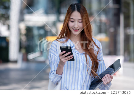 Woman is holding a cell phone and a tablet Woman is holding a cell phone and a tablet 121743085
