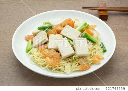 homemade style of stir fried hard tofu and egg noodles in a ceramic dish on wooden table, close up. asian food concept. homemade style of stir fried hard tofu and egg noodles in a ceramic dish on wooden table, close up. asian food concept. 121743339