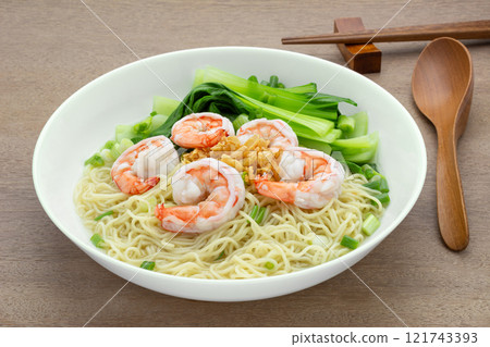 homemade style of egg noodles and shrimp with clear soup in a ceramic bowl on wooden table, close up. asian food concept. homemade style of egg noodles and shrimp with clear soup in a ceramic bowl on wooden table, close up. asian food concept. 121743393