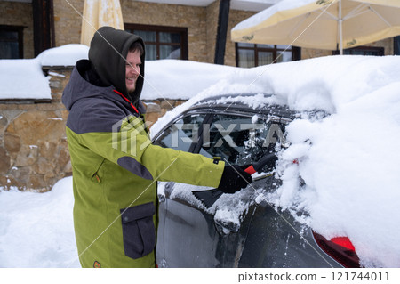 Person Clearing Snow from Car in Winter Landscape Person Clearing Snow from Car in Winter Landscape 121744011