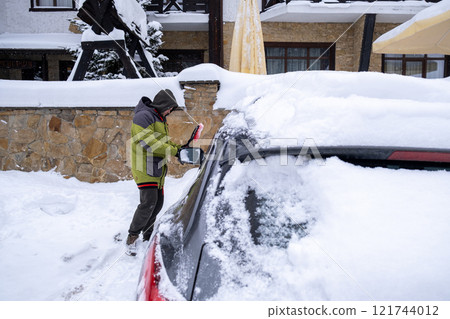 Person Clearing Snow from Car in Winter Landscape Person Clearing Snow from Car in Winter Landscape 121744012