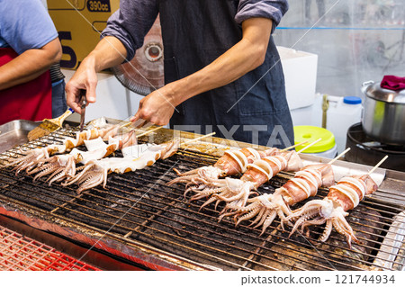 Close-up of the vendors grilling squid skewers at the night market in Taiwan.  121744934