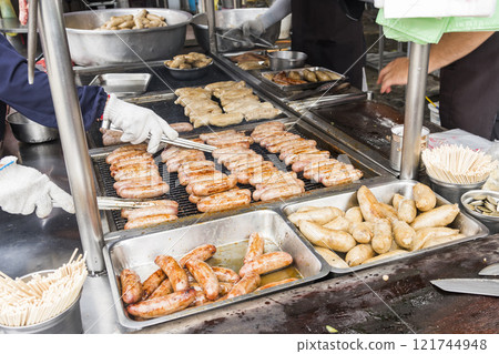 Close-up of the vendors grilling Taiwanese sausage and sticky rice (glutinous rice) sausage in the night market in Taiwan. This is one of the street snacks popular among tourists in Taiwan. Close-up of the vendors grilling Taiwanese sausage and sticky rice (glutinous rice) sausage in the night market in Taiwan. This is one of the street snacks popular among tourists in Taiwan. 121744948