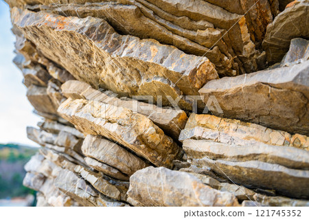 Layered rock texture in Budva, Montenegro. Sedimentary rocks with rugged surface of gray and brown. Natural formation of layers and cracks, geological structure. Layered rock texture in Budva, Montenegro. Sedimentary rocks with rugged surface of gray and brown. Natural formation of layers and cracks, geological structure. 121745352