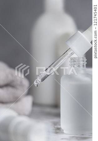 Pipette set on a glass dropper bottle on white marble near cosmetics and towel close up 121745401