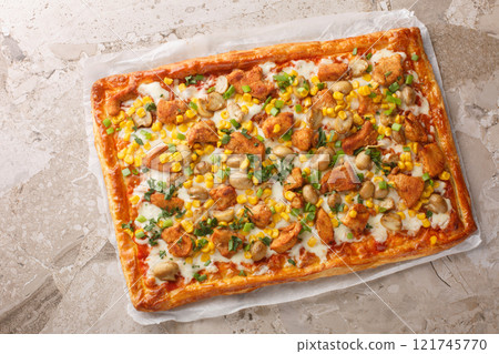 Hot puff pastry open pie with fried chicken, mushrooms, corn, mozzarella cheese and tomato sauce close-up on parchment. Horizontal top view 121745770