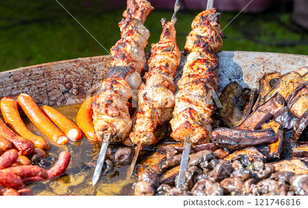 Cooking traditional appetizing hot shish kebab or shashlik on skewers. Street food and outdoor cooking 121746816