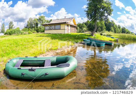 Inflatable rubber boat and other fishing boats at the shore of the lake in summer sunny day 121746829