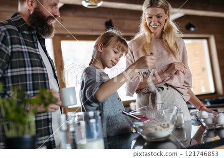 Family making pancakes for breakfast. Girl mixing, preparing pancake batter in the kitchen. Family making pancakes for breakfast. Girl mixing, preparing pancake batter in the kitchen. 121746853