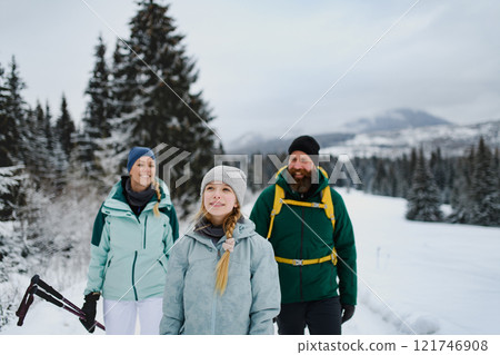 Family with daughter hiking in winter nature. Spending wither holidays in cabin. 121746908