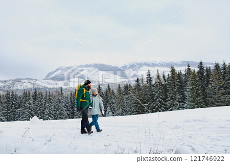 Dad and girl in the middle of snowy nature. Hiking in winter mountains. Winter family walk. 121746922