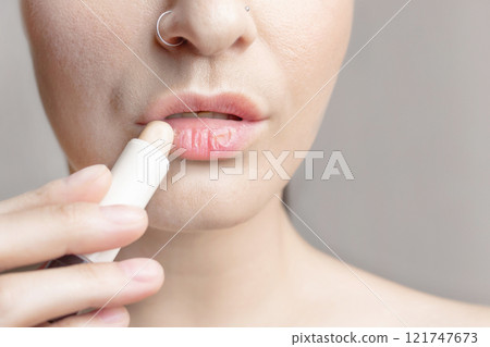 Woman with dry lips, Dry, chapped, dry skin problem with mouth disease, A woman applies a moisturizing lip balm. close up photo 121747673