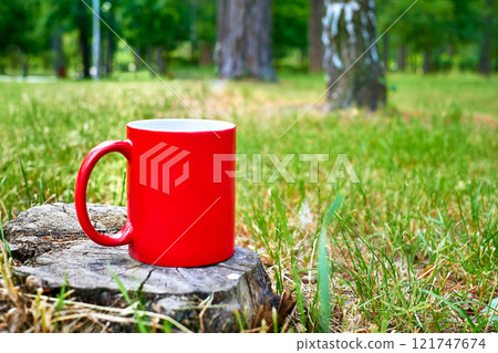 Tea time. Coffee break. Red cup mug on stump forest wild meadow  121747674