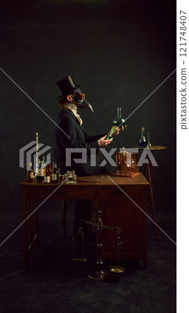 Plague doctor mixing his elements, experimenting and researching in vintage laboratory against dark mystery background. 121748407