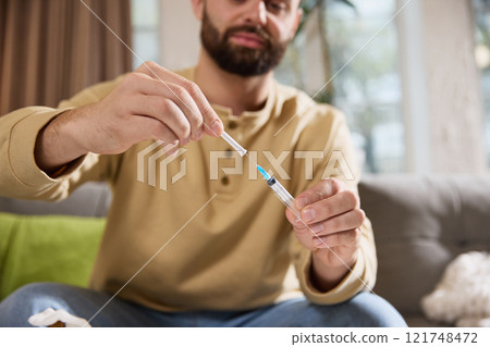 Close of male model holding medicine and clean, disinfected syringe preparing medical tools for injecting treatment at home. Close of male model holding medicine and clean, disinfected syringe preparing medical tools for injecting treatment at home. 121748472