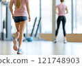 Personal trainer assists client with strength training exercises in modern gym setting 121748903