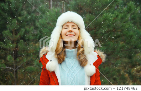 Winter day, happy smiling young woman enjoys snow, warm weather against Christmas tree background 121749462