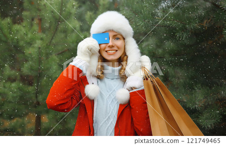 Happy smiling young woman with shopping bag, holding plastic credit bank card in winter, Christmas 121749465