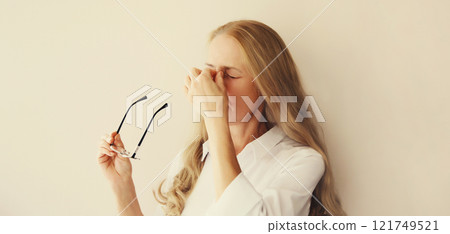 Tired overworked woman employee rubbing her eyes suffering from eye strain, dry eye syndrome Tired overworked woman employee rubbing her eyes suffering from eye strain, dry eye syndrome 121749521