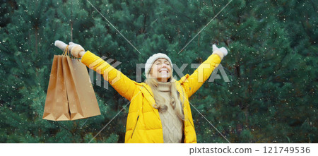 Happy smiling young woman with shopping bag in winter against Christmas tree, holiday shopping Happy smiling young woman with shopping bag in winter against Christmas tree, holiday shopping 121749536