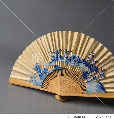 Traditional folding fan with blue floral patterns on beige background.  121749673